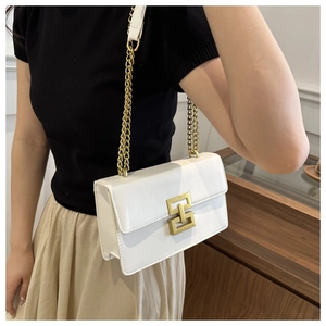 Detailed view of white leather crossbody bag with gold interlocking buckle and chain strap