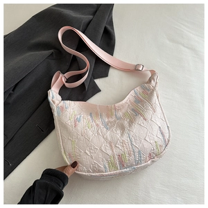 Detail of pink half-moon bag featuring colorful embroidery and logo embossed nylon texture