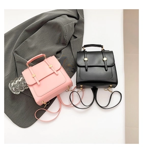 Detail of pink and black preppy backpacks with gold buckles on a grey blazer