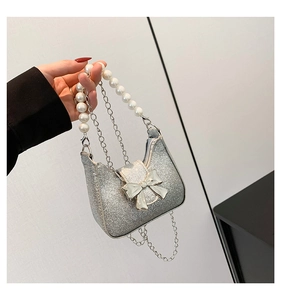 Detail of silver sequin mini bag featuring pearl handle and metallic bow accent