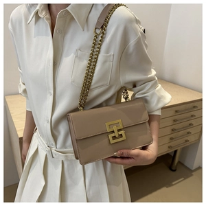 Detail showing the light brown leather crossbody bag with iconic gold geometric clasp