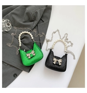 Detail of glitter mini bag with pearl handle and silver bow in green and black