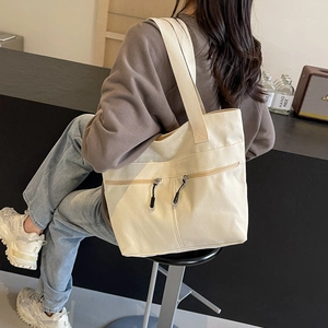 Minimalist beige canvas tote bag with front zipper pockets for casual daily commute