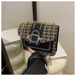 Close-up of plaid tweed and black leather bag with gold buckle and chain strap
