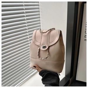 Détail d'un mini sac à dos beige clair avec poignée chaîne et fermoir pivotant en métal