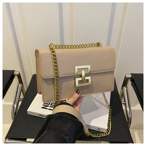 Detail of beige leather crossbody bag with golden chain and geometric metal clasp