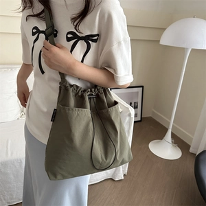 Army green large canvas drawstring crossbody bag with front pockets and workwear style