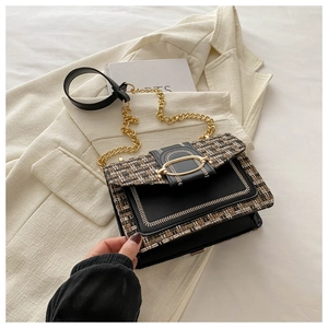 Detail of tweed and black leather patchwork bag with golden chain and oval metal clasp