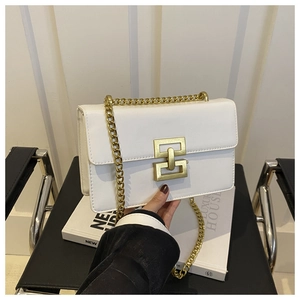 Detail of white leather shoulder bag with gold chain strap and geometric twist lock closure