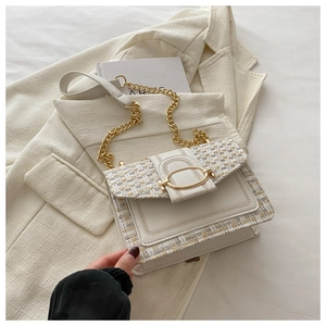 Detail of tweed crossbody bag with gold chain strap and metal clasp on beige blazer