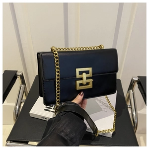 Close-up of retro black matte leather shoulder bag with gold geometric buckle and chain