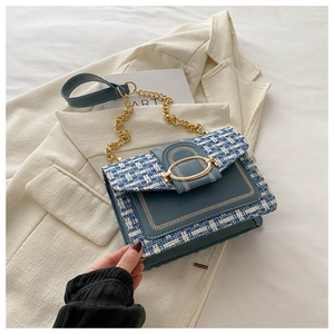 Detail of blue tweed and leather crossbody bag with gold chain and oval metal clasp