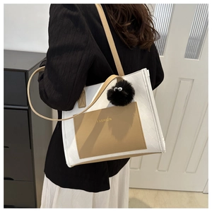 Detail of white textured tote bag with khaki pocket and black fuzzy eye charm