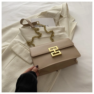 Close-up of beige leather crossbody bag with vintage golden metal chain and lock buckle