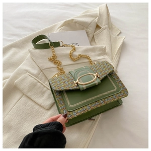 Detail of green tweed crossbody bag with gold chain and circular clasp on white blazer
