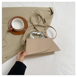 Détail du sac bandoulière beige avec poignée métallique argentée irrégulière et lanière