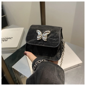 Close-up of mini black crossbody bag featuring a vintage silver butterfly metal buckle
