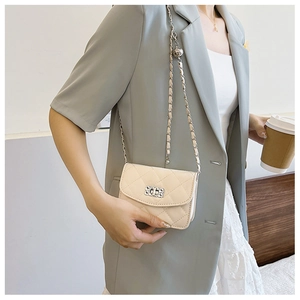 Close-up of beige quilted crossbody bag with silver leather-interwoven chain strap