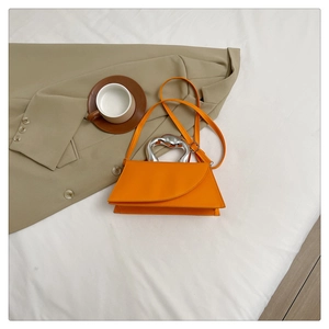 Gros plan sur sac à main orange en cuir avec poignée sculpturale en métal argenté