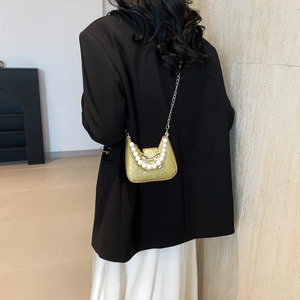 Mini gold sequin crossbody bag with pearl handle and bow clasp on black blazer outfit