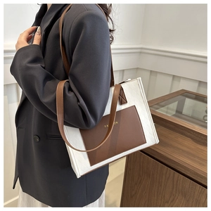 Detail of woven tote bag featuring brown leather pocket with FASHION text and shoulder strap