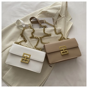 Close-up of white and beige crossbody bags with golden interlock buckle and chain strap