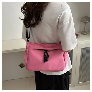Pink nylon crossbody tote bag with adjustable black strap and zipper detail shown on model