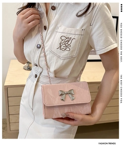 Pale pink mini crossbody bag with silver butterfly buckle shown on model's shoulder