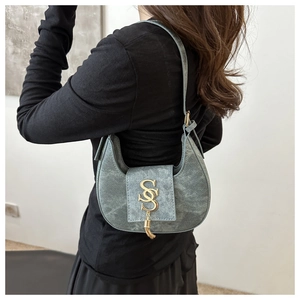Dettaglio borsa a mezzaluna blu con hardware dorato a S e decorazione con elegante nappa