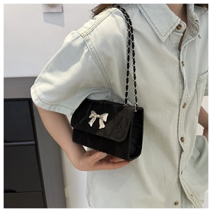 Detail shot of the black ruched crossbody bag with a silver butterfly accent on the strap