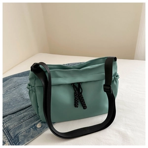 Detail of mint green oxford shoulder bag featuring black drawstring and adjustable strap