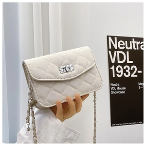 Detail of white quilted crossbody bag with silver rotating lock and chain strap