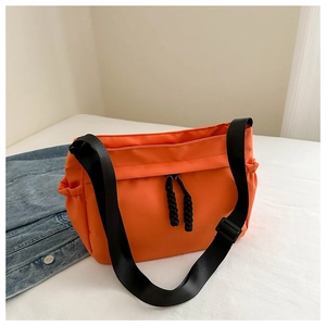 Detail of orange nylon tote bag with black woven drawstring and adjustable wide strap
