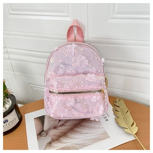 Detail eines rosa Paillettenrucksacks mit Wellenmustern und floralen Applikationen