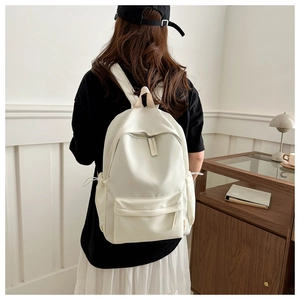 Rear view of minimalist white Oxford backpack worn by a model in a cozy indoor setting
