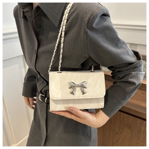 Ivory pleated chain shoulder bag featuring a silver metal butterfly on the side view
