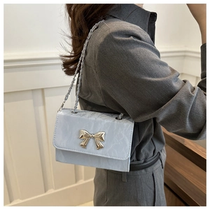 Detail of light blue crossbody bag with silver bow buckle and marble texture