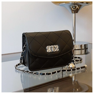 Detailed macro of black quilted leather texture and silver metallic twist lock on flap bag