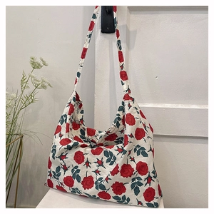 Floral canvas tote bag with red roses hanging on a white wall in a minimalist setting