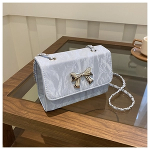 Detailed view of blue wrinkled texture and silver butterfly buckle on chain bag