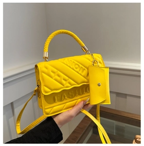 Detail of yellow quilted tote bag with FASHION embossment and matching charm pouch