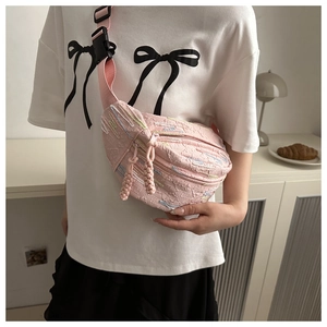 Detail of pink crossbody dumpling bag with colorful textured fabric and woven zipper pull