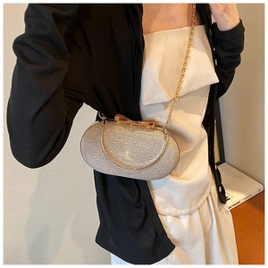 Detailed view of a gold glitter evening clutch bag with an elegant bow clasp and ring handle