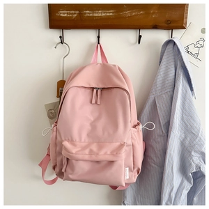 Pink minimalist Oxford backpack with waterproof fabric hanging on a wooden hook