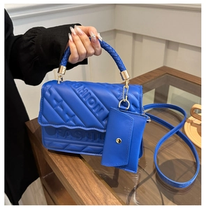 Detail of blue quilted leather bag showing FASHION embossed texture and woven handle