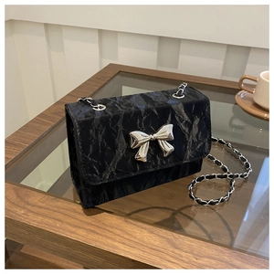 Detail of black pleated texture shoulder bag featuring a silver metal butterfly clasp