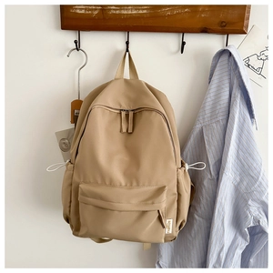 Detailed view of the khaki Oxford fabric backpack hanging with drawstring side pockets