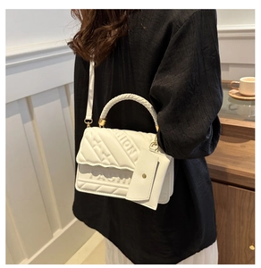 Close-up of a white quilted handbag with embossed fashion lettering and a mini coin purse