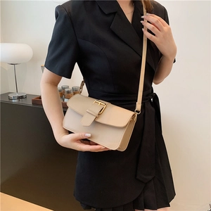 Minimalist beige leather rectangular crossbody bag with a gold buckle on model