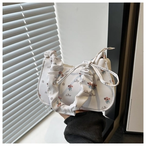 Detail of white floral shoulder bag featuring bow tie and ruched cloud handle